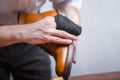 Closeup of Mans Hands with Cleaning Cloth Used for Polishing Tan High Derby Boots. Against Grey