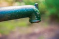 Closeup manual old green and rusty water lever pump with water pouring out of the spout, last drop of water, drought Royalty Free Stock Photo