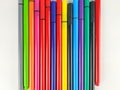 Closeup of many colorful pens with caps and vivid colors lined randomly on white background used by students and kids for note Royalty Free Stock Photo