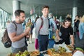 Closeup many passengers try snacks from free degustation table in Lviv airport hall