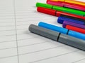 Closeup of many pens with different colors laying on the top of the white empty notebook with lines for better note taking and fun Royalty Free Stock Photo