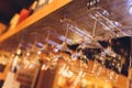 Closeup many upside down empty clear transparent crystal upturned wine glasses hanging in straight rows on brown wooden