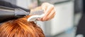 Closeup of master& x27;s hand with blow-drying and hairbrush blowing female red hair in a salon. Royalty Free Stock Photo