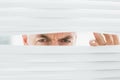 Closeup of a mature businessman peeking through blinds