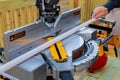 Close up of mature man sawing lumber with sliding compound miter saw outdoors, sawdust flying around