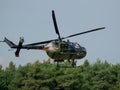 Closeup of MBB Bo105 helicopter releasing paint above green trees at an air show in Slovakia