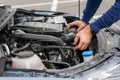 Closeup of mechanic hands checking motor under the hood in the broken car. Repairing of the vehicle concept. Automobile service.