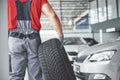 Closeup of mechanic hands pushing a black tire in the workshop Royalty Free Stock Photo