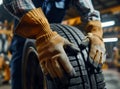 Closeup of mechanic hands pushing a black tire in the workshop. Royalty Free Stock Photo