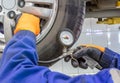 Closeup of mechanic at repair service station checking tyre pressure with gauge Royalty Free Stock Photo