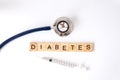 Closeup medical stethoscope and Wooden letter block word diabetes with insulin syringe on white background using as diabetes,