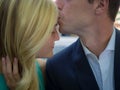 Closeup of a man kissing the forehead of a woman under sunlight with a blurry background