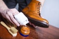 Closeup of Mens hands Polishing Leather Tanned Derby Brogue Boots. using variety of Brushes and Polishing Wax