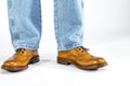 Closeup of Mens Legs on Brown Oxford Brogue Shoes. Posing in Blue Jeans Against White Background Royalty Free Stock Photo