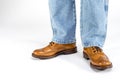 Closeup of Mens Legs on Brown Oxfords Brogues Shoes. Posing in Blue Jeans Against White Background Royalty Free Stock Photo