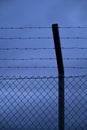 A closeup of a metal barbed wire fence against dramatic strorm clouds