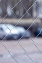 Closeup of metal chainlink fence with cars in background, electric blue tint Royalty Free Stock Photo