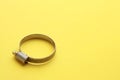 Closeup of a metal plumber clamp on a bright yellow background