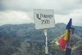 Closeup Of A Metal Sign With The Height Of The Peleaoa Mountain With A Romanian Flag Next To It