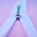 Closeup of a metal zip isolated on a pink background. Macro view of a zipper closing or being unzipped on fabric in a Royalty Free Stock Photo