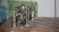Closeup of metallic chess pieces on a dusty board under the lights with a blurry background Royalty Free Stock Photo