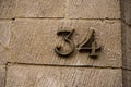 metallic number 34 on stoned wall of building Royalty Free Stock Photo