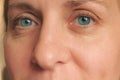 Closeup of middle aged woman face with blue eyes. Real skin without make up and correction. Look at camera. Smiled