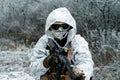 Closeup military man in white camouflage uniform with hood and machinegun. Horizontal photo