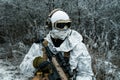 Closeup military man in white camouflage uniform with machinegun