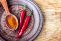 Closeup milled chili peppers flakes and chili powder on dark plate, fresh red ripe hot chili on old wood board background with cop