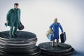 Miniature woman and man on piles of dollar coins