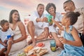 Closeup of a mixed race family having a picnic on the beach and smiling while having some food with snacks. Happy family Royalty Free Stock Photo