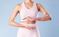 Closeup mixed race fitness woman gesturing around her tummy in studio against a blue background. Young hispanic female Royalty Free Stock Photo