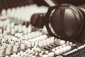 Closeup mixing console with headphones on top, faders and knobs background, artistic studio equipment concept