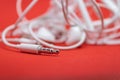 Closeup of 3.5 mm input plug from the earphones compatible with mp3 players and phones on the red background