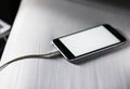 Closeup of mobile phone charging and lying on white fabric background Royalty Free Stock Photo