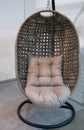 Closeup modern armchair in shape of eggshell or birds nest made of woven bamboo, Wicker, Rattan swinging hanging on a stand with