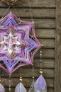 Closeup modern dreamcatcher star mandala with amethyst and peacock feathers on wooden background