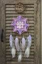 Closeup modern dreamcatcher star mandala with amethyst and peacock feathers on wooden background