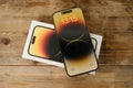 Closeup modern gadget apple on wooden table, unpacks, testing new gold smartphone iPhone 14 Pro Max with Super Retina display,