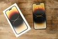 Closeup modern gadget apple on wooden table, unpacks, testing new gold smartphone iPhone 14 Pro Max with Super Retina display,