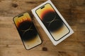 closeup modern gadget apple on wooden table, unpacks, testing new gold smartphone iPhone 14 Pro Max with Super Retina display,