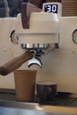 Closeup of modern professional espresso machine with coffee pouring into take away paper cup Royalty Free Stock Photo