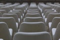 Closeup of a modern white auditorium filled with rows of chairs under the natural light