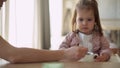 Closeup mom feed young baby in white feeding up high chair, kid is trying to eat himself, happy child with food stained Royalty Free Stock Photo