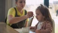 Closeup mom feed young baby in white feeding up high chair, kid is trying to eat himself, happy child with food stained Royalty Free Stock Photo