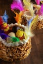 Closeup of a mona de pascua, a cake eaten in Spain on Easter Monday, ornamented with feathers and a teddy chick on on a rustic