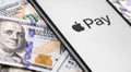 Closeup money and iPhone with Apple Pay logo. Apple Pay is a mobile payment and digital wallet service by Apple Inc. Moscow,