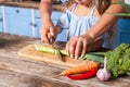 Closeup of mother and child chopping vegetable with knife on board, cooking healthy breakfast together