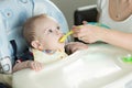 Closeup of mother giving porridge to her baby boy from plastic s Royalty Free Stock Photo